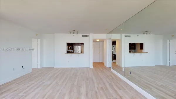 a view of a big room with wooden floor and windows