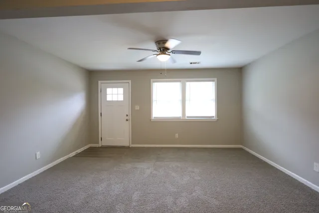 an empty room with a window and a fan