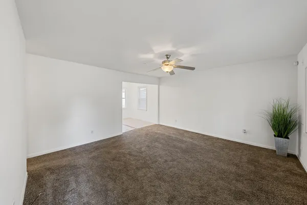 a view of an empty room with a chandelier fan