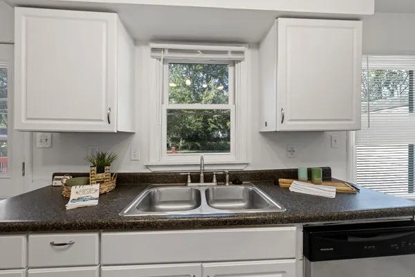 a kitchen with granite countertop stainless steel appliances white cabinets sink and window