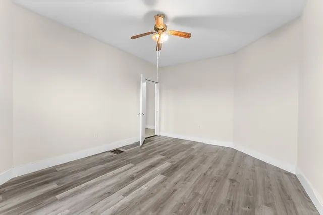 a view of a room with wooden floor and a ceiling fan