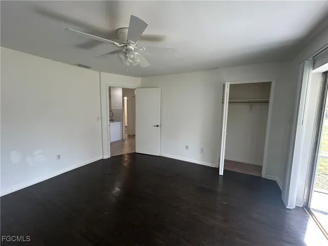 an empty room with wooden floor closet and windows