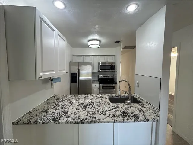 a kitchen with kitchen island a counter top space cabinets and stainless steel appliances