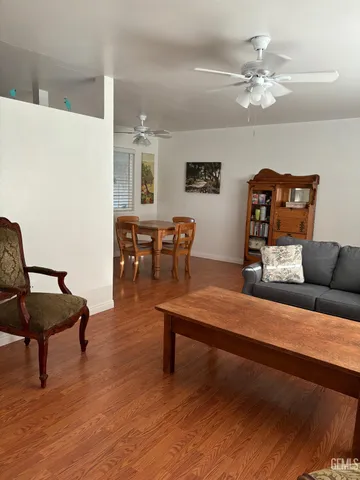 a living room with furniture and a dining table with wooden floor