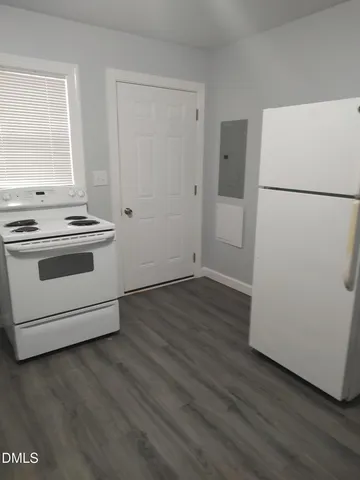 an empty room with wooden floor and a stove top oven