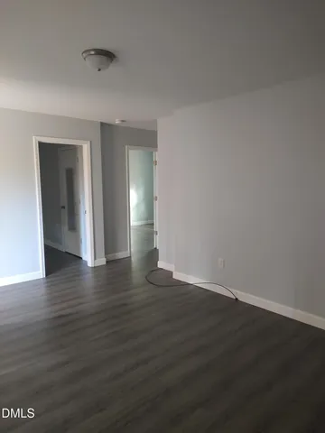 a view of an empty room with wooden floor and closet
