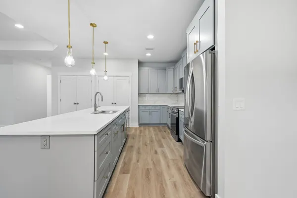 a large kitchen with a sink a counter space stainless steel appliances and cabinets