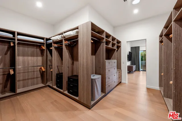 a view of walk in closet with clothes and white walls
