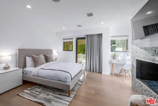 a spacious bedroom with a bed a flat screen tv and a fireplace