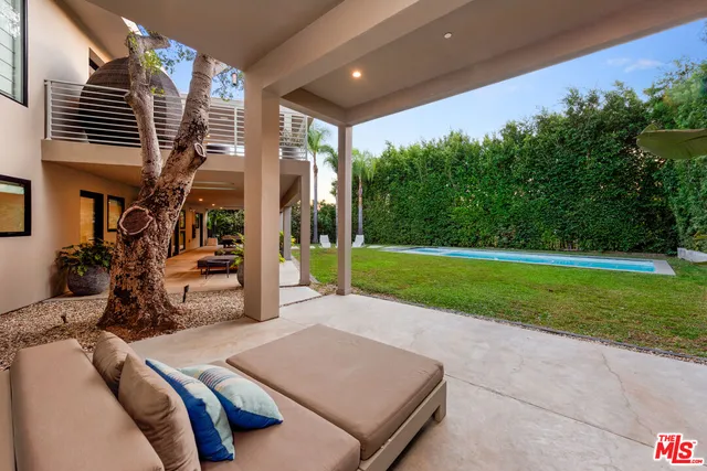 a view of a backyard with couches plants and large tree