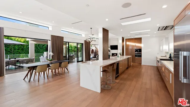 a large white dining hall with stainless steel appliances granite countertop a stove and a wooden floors