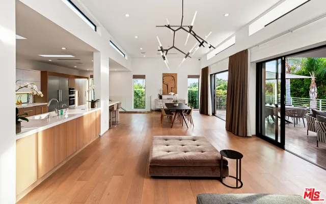 a living room with furniture appliances chandelier and wooden floor