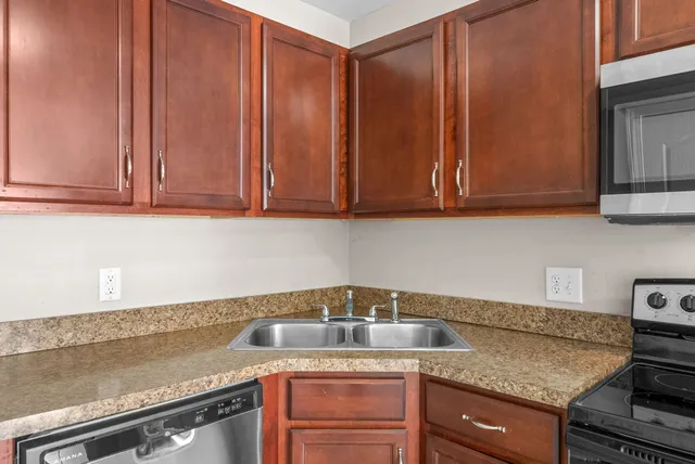 a kitchen with granite countertop a sink cabinets and stainless steel appliances
