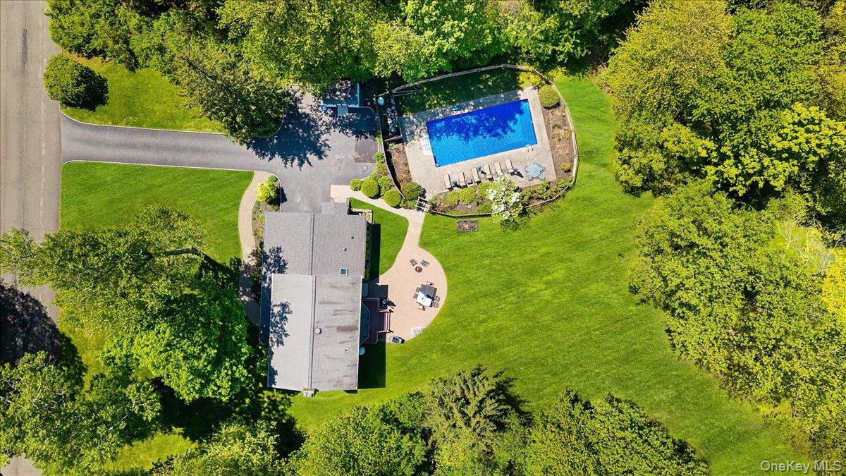 Aerial view of 119 Edgewood Road. Vacation at home! A gorgeous heated in-ground pool is already open for the season. There's a large rear paver patio and an acre of lush lawn surrounded by trees. Not another home in sight and yet you're in a beautiful tree-lined residential neighborhood.