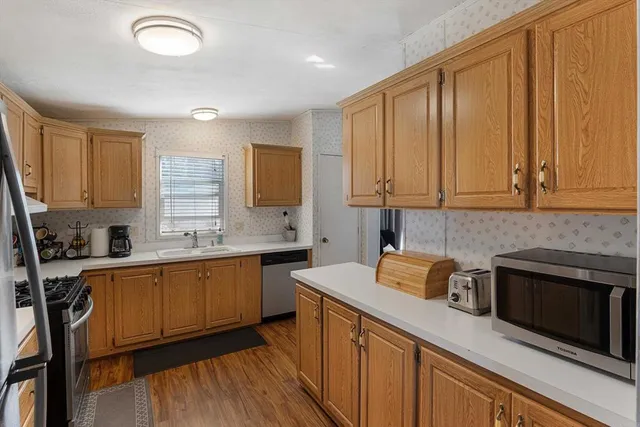 a kitchen with stainless steel appliances granite countertop wooden cabinets a sink and dishwasher a stove with wooden floor