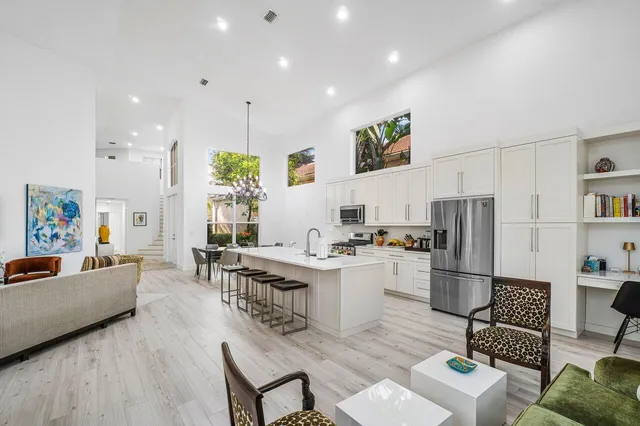 a kitchen with stainless steel appliances a white refrigerator a stove a dining table and chairs with wooden floor