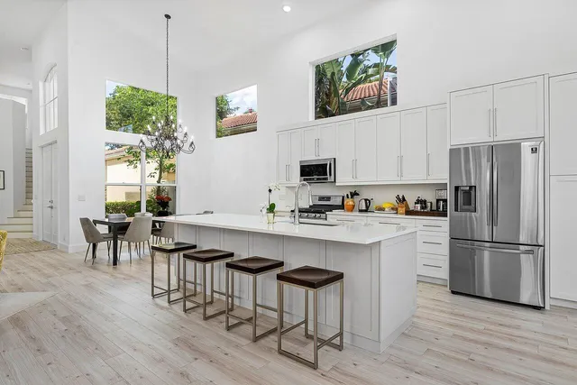 a kitchen with stainless steel appliances a stove a sink dishwasher a oven with white cabinets and wooden floor