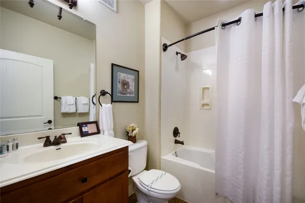 a bathroom with a sink a toilet a mirror a bathtub and shower