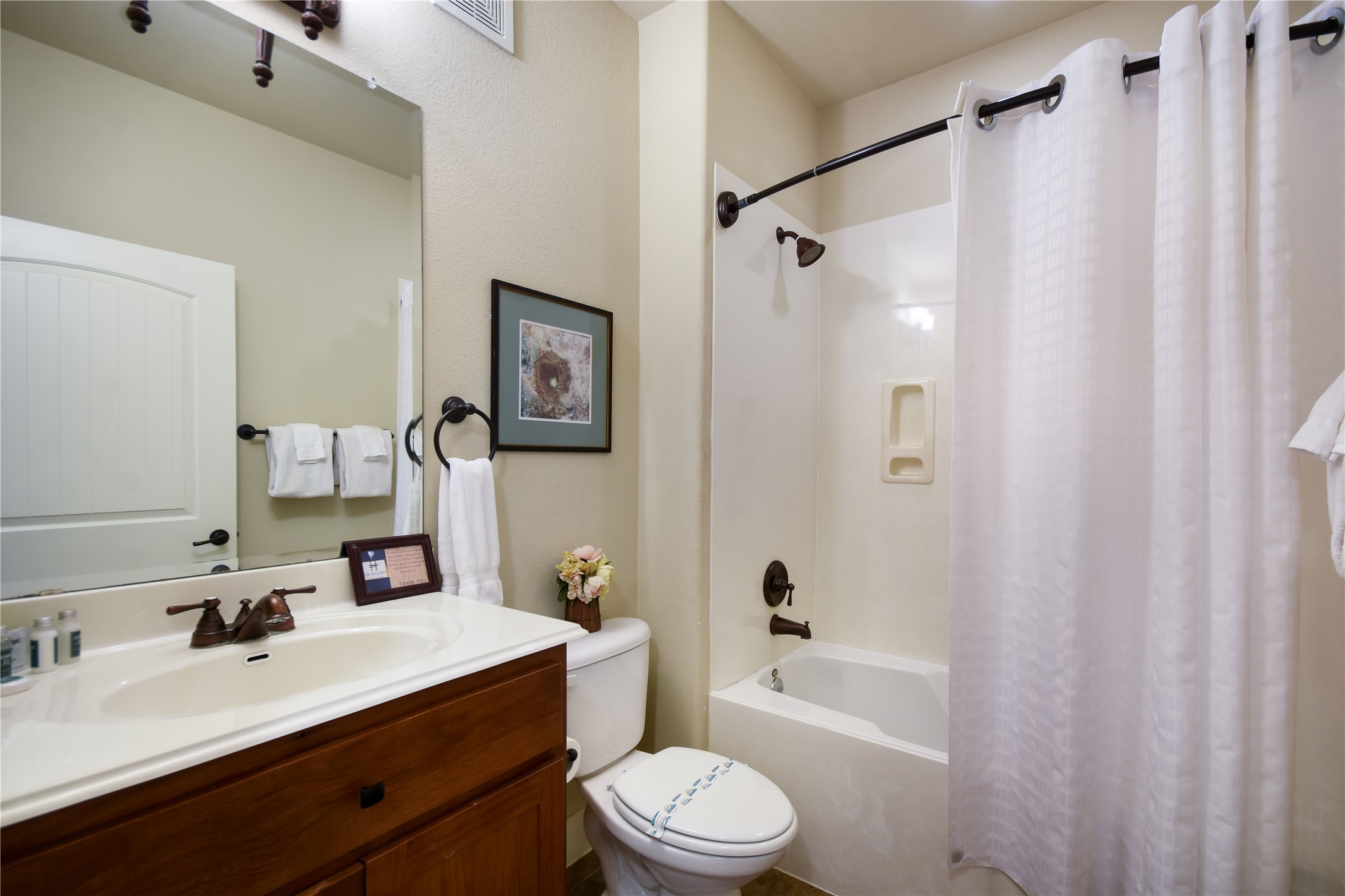 17800 Edgewood Way, Unit 203 Jonestown, TX 78645 - Photo 19 of 40 a bathroom with a sink a toilet a mirror a bathtub and shower