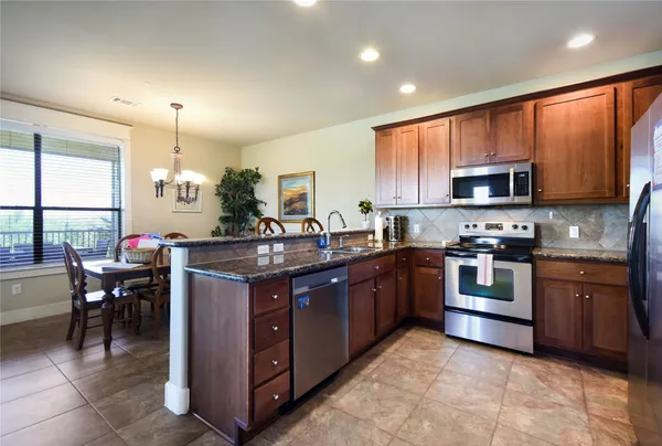 a kitchen with stainless steel appliances granite countertop a refrigerator a stove top oven a sink and dishwasher