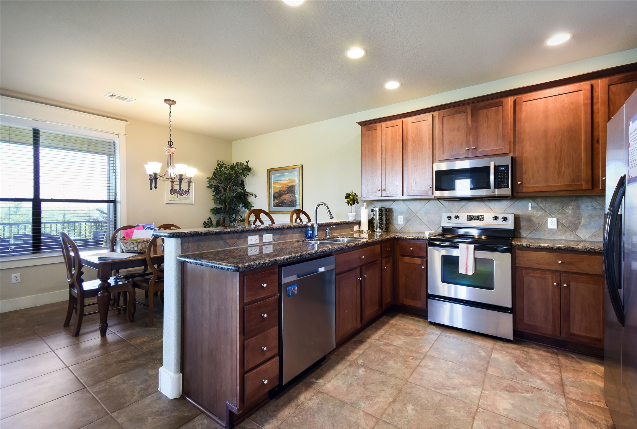 17800 Edgewood Way, Unit 203 Jonestown, TX 78645 - Photo 5 of 40 a kitchen with stainless steel appliances granite countertop a stove top oven a sink dishwasher a dining table and chairs
