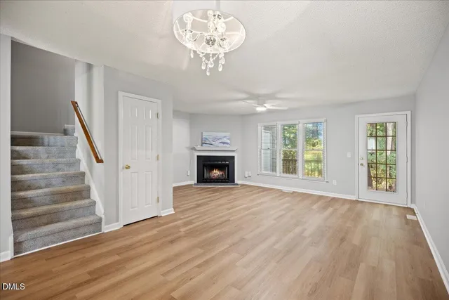 a view of an empty room with wooden floor fireplace and a window