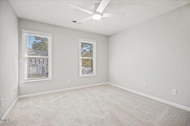 an empty room with windows and fan