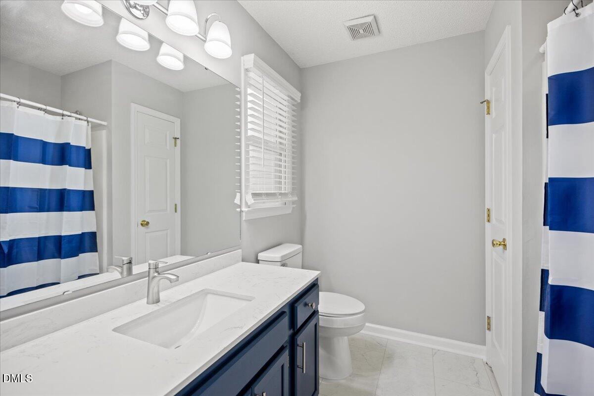 6063 Epping Forest Drive Raleigh, NC 27613 - Photo 22 of 34 a bathroom with a sink a toilet a mirror a vanity and shower