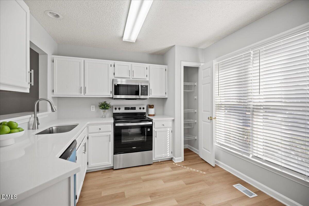 6063 Epping Forest Drive Raleigh, NC 27613 - Photo 4 of 34 a kitchen with a sink a stove and cabinets