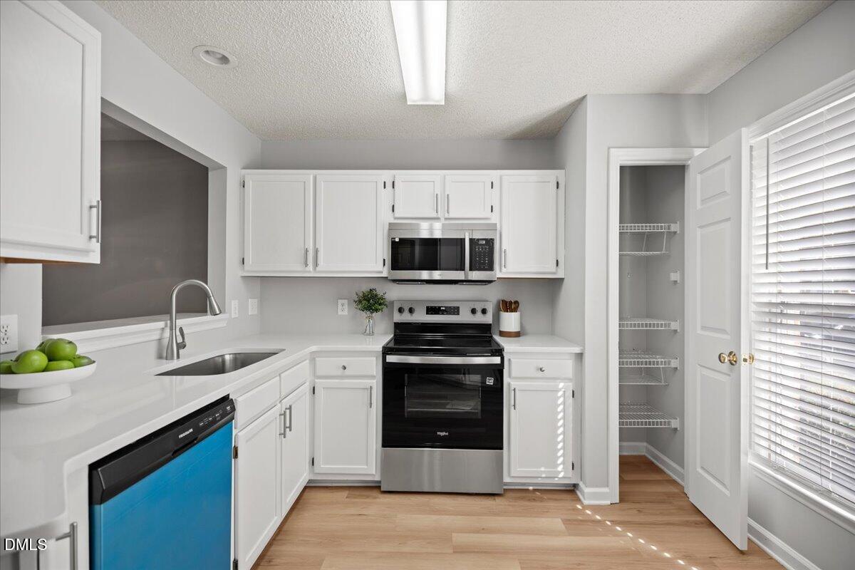 6063 Epping Forest Drive Raleigh, NC 27613 - Photo 5 of 34 a kitchen with stainless steel appliances a stove a sink and a microwave
