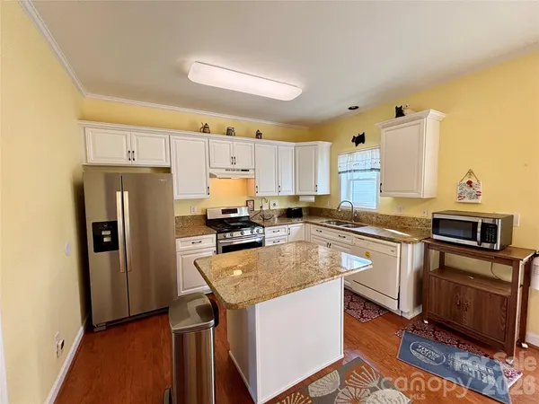 a kitchen with granite countertop a refrigerator a stove and a sink
