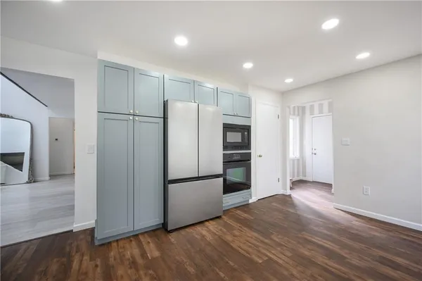 a view of a kitchen with a refrigerator and wooden floor cabinets