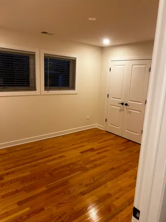 a view of an empty room with wooden floor and windows