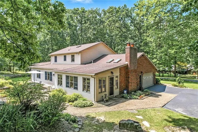 a view of a big yard in front of a brick house with large windows