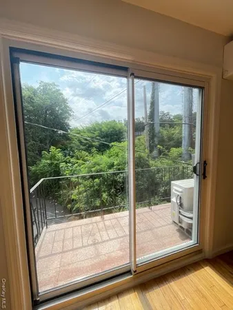 a view of a room with a large window and wooden floor