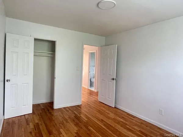 a view of an empty room with wooden floor and closet