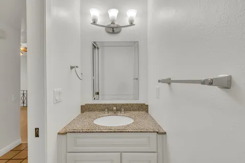 a bathroom with a granite countertop sink and a mirror