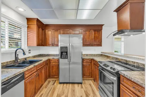 a kitchen with stainless steel appliances granite countertop a stove a sink dishwasher and a refrigerator