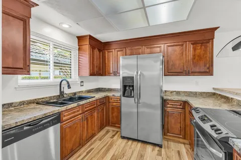 a kitchen with granite countertop a sink stainless steel appliances and cabinets