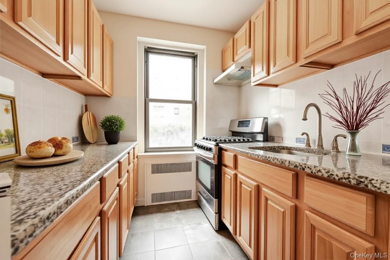 96-11 65th Road, Unit 1 Queens, NY 11374 - Photo 3 of 10 a kitchen with granite countertop a sink a stove and cabinets