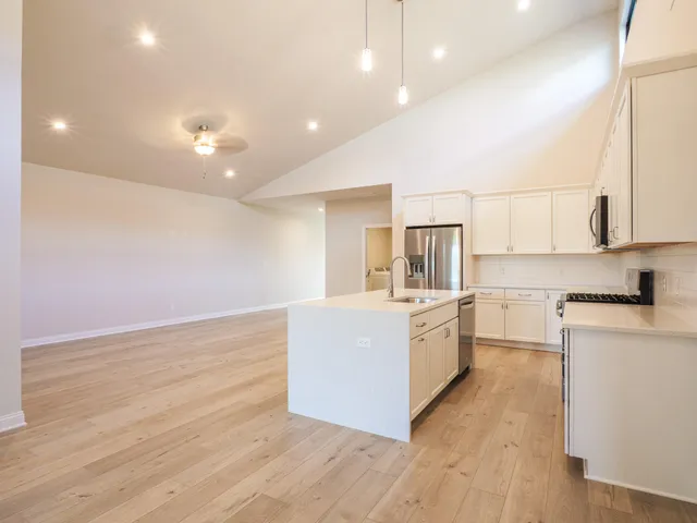a large kitchen with cabinets wooden floor and stainless steel appliances