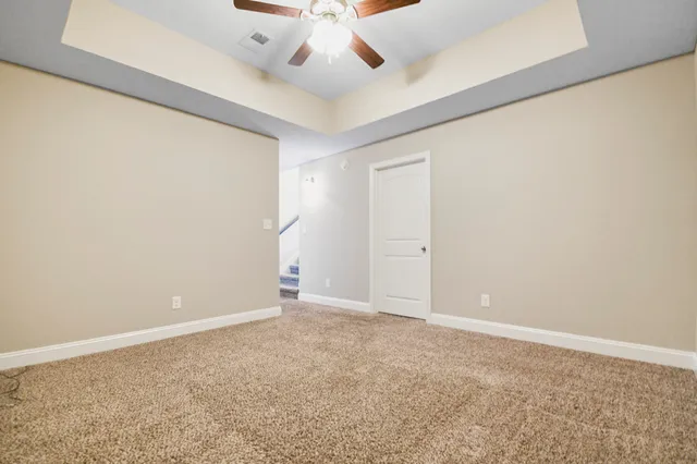 an empty room with a ceiling fan and carpet