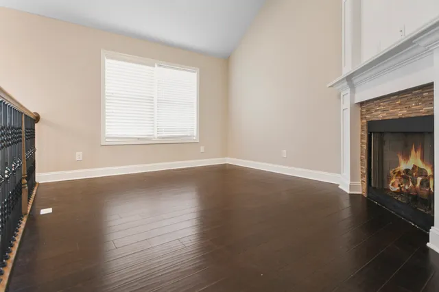 an empty room with wooden floor fireplace and windows