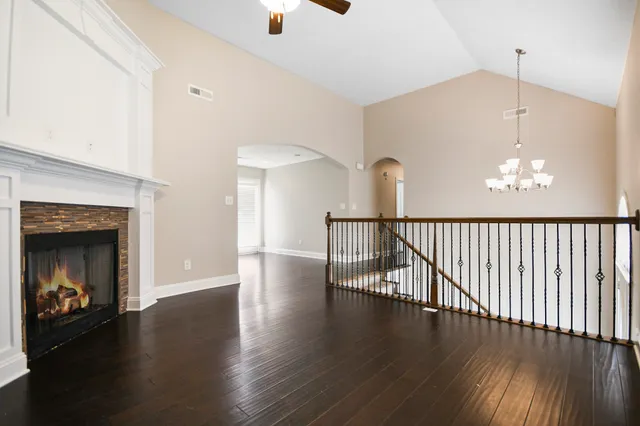 an empty room with wooden floor fireplace and windows
