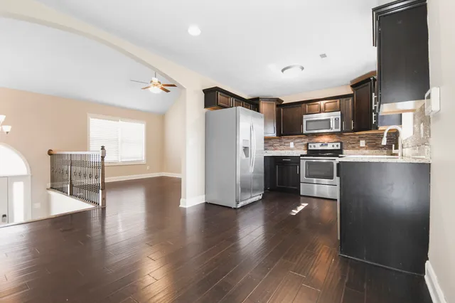 a kitchen with stainless steel appliances granite countertop a refrigerator a stove top oven a sink dishwasher and white cabinets with wooden floor