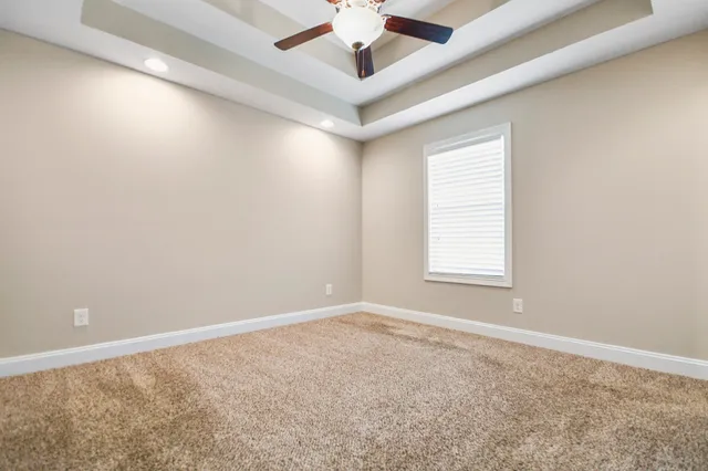 an empty room with a chandelier fan and windows