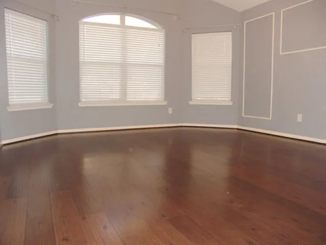 an empty room with wooden floor and windows