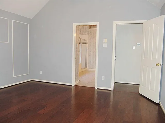 an empty room with wooden floor & closet area