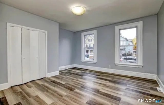 a view of an empty room with window and wooden floor