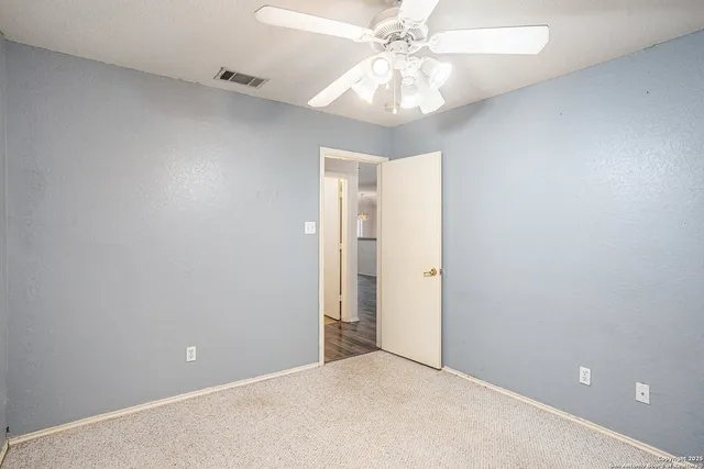 an empty room with a chandelier fan and closet area